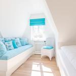 Ein Schlafzimmer mit Bett, Sitzbank und Fenster unter Dachschräge.