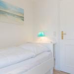 Schlafzimmer mit weißem Bett, Wandbild und Lampe.