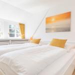Schlafzimmer mit Doppelbett, Fenstern und Wandbild