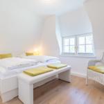 Schlafzimmer mit Doppelbett, Sitzbank und Stuhl. Fenster mit Blick nach draußen.
