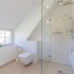 Badezimmer mit Dusche, Toilette und Fenster