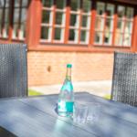 Außentisch mit Wasserflasche und Gläsern vor einem Haus