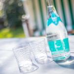 Auf dem Tisch stehen ein Wasserglas, ein weiteres Glas und eine Wasserflasche.
