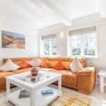 Wohnzimmer mit orangefarbenem Sofa, weißem Couchtisch und Fenstern.