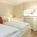 Room with two beds, window with roller blind and lamp on windowsill.