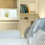 A bed with pillows and a bookcase in the background.