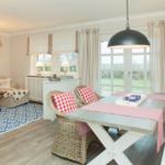 Dining area with table and chairs, seating with cushions and window for view.