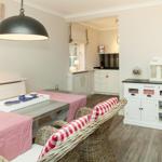 Dining area with table, chairs, and kitchen in the background.