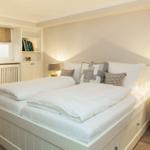 A bedroom with a double bed, nightstands, and a window with blinds.
