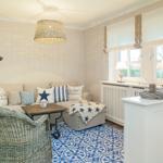 Living room with sofa, cushions, table, and chair on blue-and-white rug.