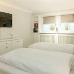 Bedroom with double bed, TV, and window with blinds.