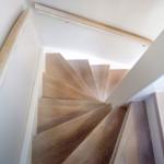 Holztreppe mit Geländer führt nach oben.