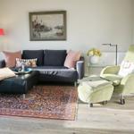 Ein Wohnzimmer mit Sofa, Sessel, Teppich und Wandbild.