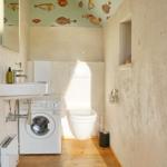 Badezimmer mit Waschmaschine, WC und Fischmotiv an der Decke.