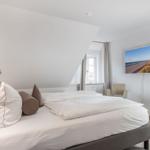 Schlafzimmer mit Doppelbett, Wandbild und Sitzgelegenheiten.