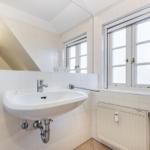Badezimmer mit Waschbecken, Spiegel und Fenster.