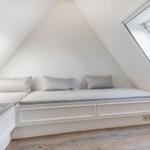 Schlafzimmer mit Dachschrägen, weiße Matratzen und Fenster