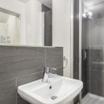 Badezimmer mit Waschbecken, Spiegel und Dusche.