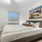 Schlafzimmer mit Bett, Wandbild und Fenster