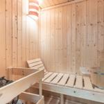 Sauna mit Holzbank, Steinmulde und Eimer.