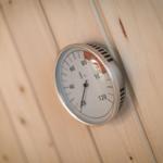 Thermometer an Holzwand in Sauna zeigt Temperatur an.