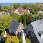 Haus mit Dachgauben und Garten, Blick aufs Meer und umliegende Häuser.