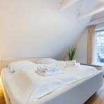 Schlafzimmer mit Doppelbett, Fenster und Holzboden.