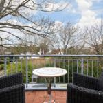 Terrasse mit zwei Stühlen und Tisch, Blick auf Bäume und Häuser