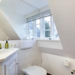 Badezimmer mit Waschbecken, Toilette und Fenster mit Blick nach draußen.