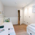 Room with two beds, closet, and wooden floor.