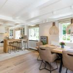 Kitchen and dining area with wooden table, chairs, and hanging lamps.