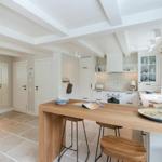 Kitchen with wooden island, white cabinets, stone floor