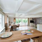 Bright kitchen with dining area and living room with TV and balcony door.