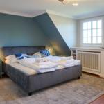 Schlafzimmer mit Bett, Nachttisch und Fenstern