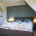 Schlafzimmer mit Doppelbett, zwei Nachttischen und Wandbild.
