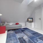 Schlafzimmer mit Dachschräge, Sofa, Teppich und Fernseher.