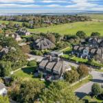 Dorf mit strohgedeckten Häusern und grünen Wiesen am Wasser.
