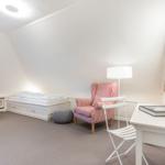 Schlafzimmer mit Bett, Sessel, Schreibtisch und TV.