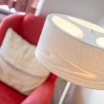 Rote Sitzgelegenheit mit Kissen und beleuchteter Stehlampe.