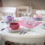 Runde weiße Tischplatte mit rosa Geschirr und Gläsern.