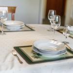 Table set with plates, glasses, and cutlery on tablecloth.