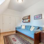 Bedroom with blue sofa, bookshelf, and TV.