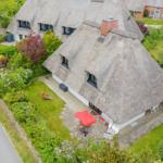 Thatched house with garden and terrace with red umbrella.