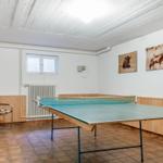 Ping pong table with net, wall pictures and window in room.
