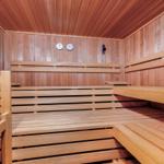 Wooden sauna with multiple benches and two thermometers on the wall.