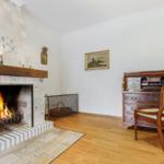 Room with fireplace, hardwood floor, and writing desk furniture.