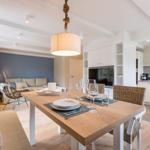 Dining area with table and chairs. Kitchen and living area in background.