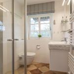 Bathroom with shower, toilet, sink, and window.