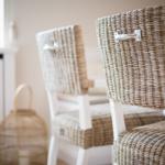 Two wicker chairs with white legs are at a table.