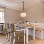 Dining room with wooden table, bench, and wicker chairs.